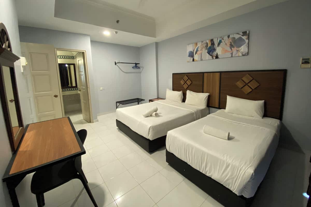A hotel room with two beds, a desk, and a ceiling fan.