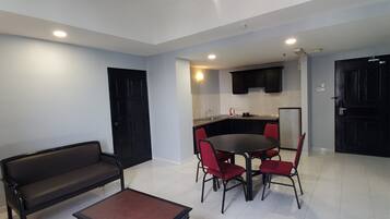 A compact living space with a dining area, kitchenette, and a black door.