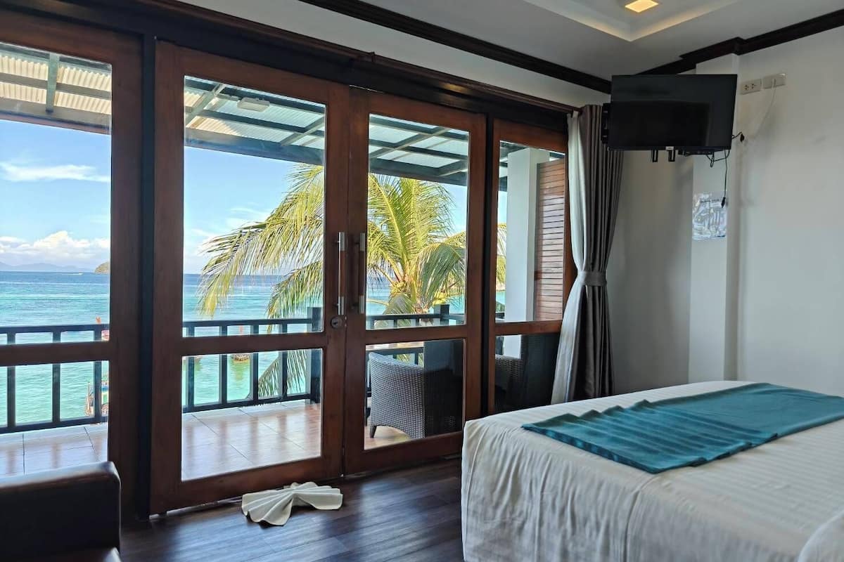 A bedroom with a bed, a TV, and a view of the ocean.