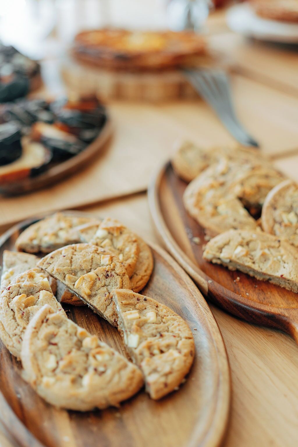 Une table en bois sur laquelle se trouvent plusieurs assiettes de nourriture, notamment des biscuits et une tarte.