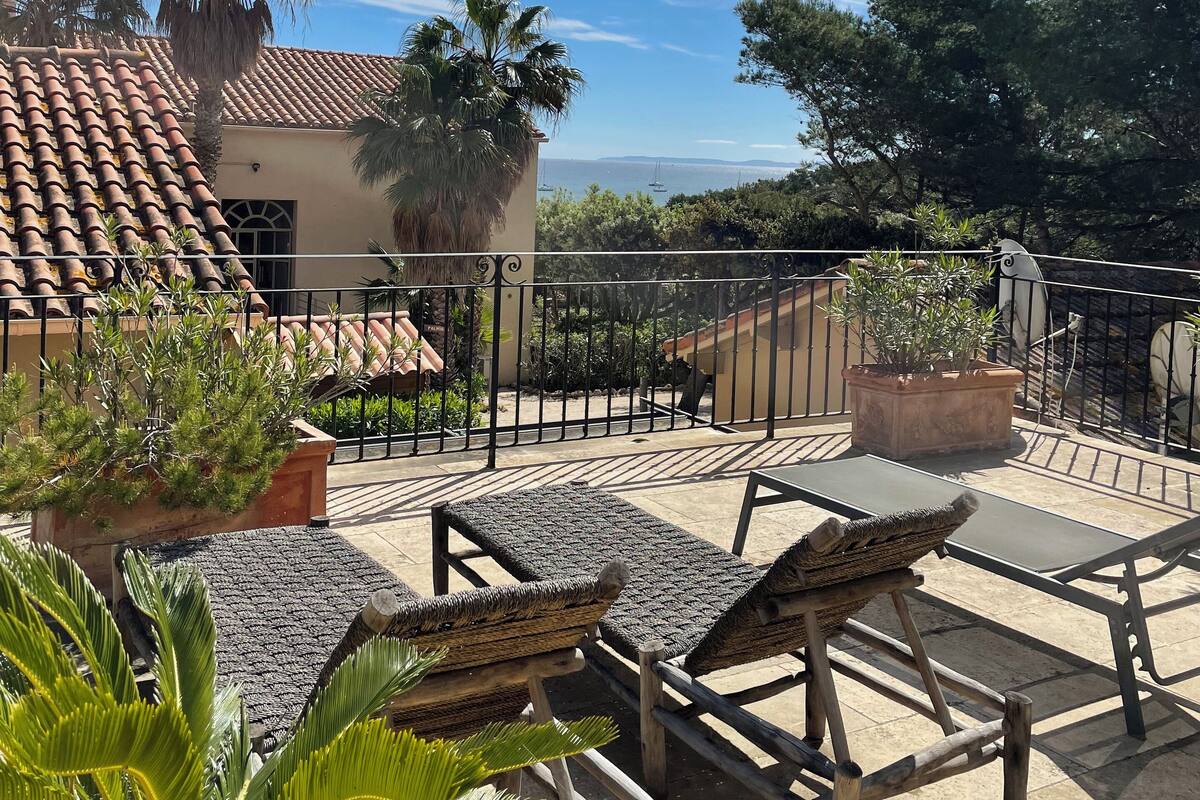 A patio with outdoor furniture, a railing, and a view of the ocean.