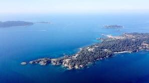 An aerial view of a coastal area with a densely forested peninsula, clear blue waters, and several small islands. - Le Domaine de la Mer (Hyères)