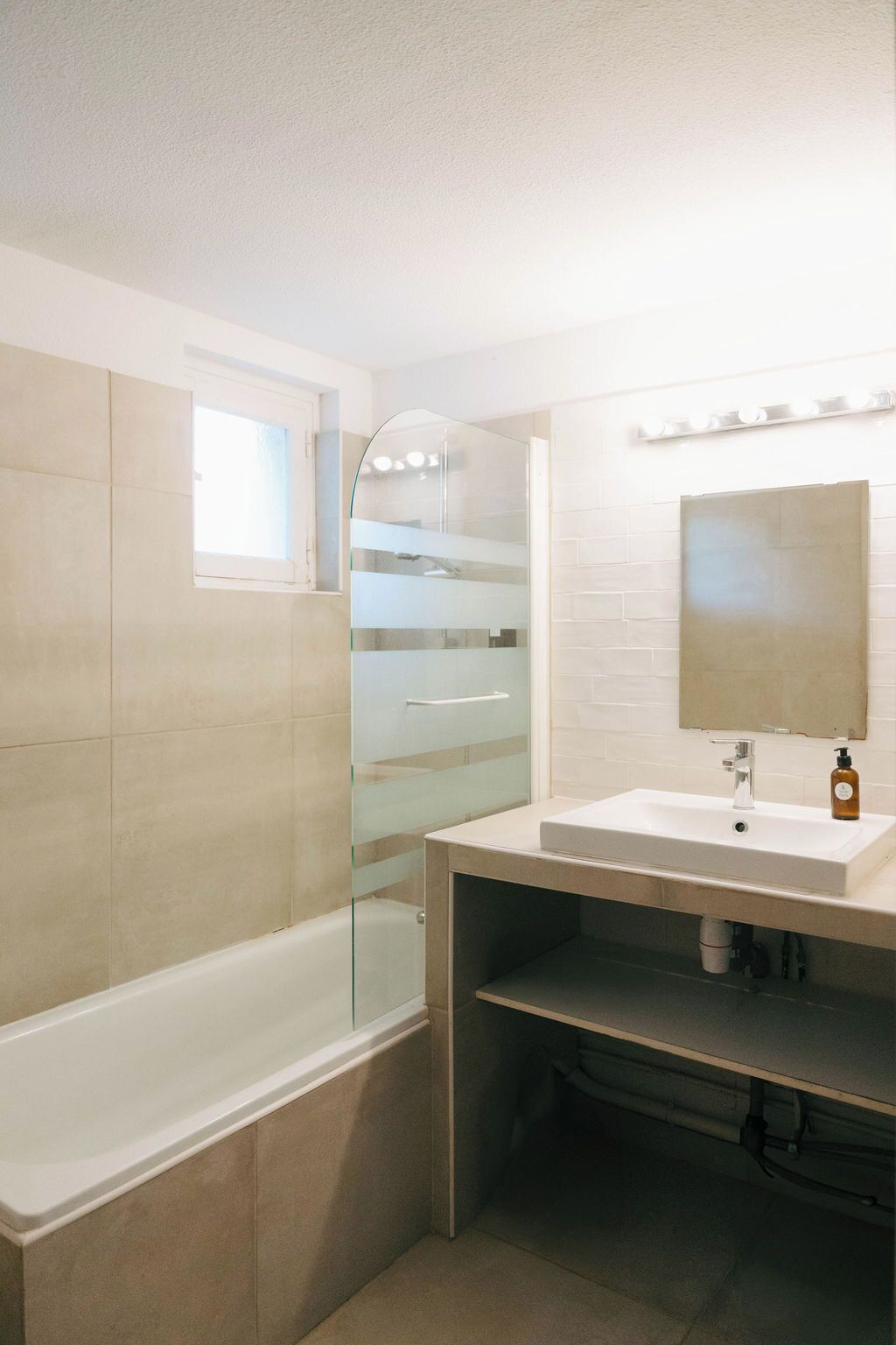 A modern bathroom with a glass shower enclosure, a bathtub, a vanity with a mirror, and a sink.