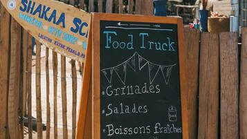 Un camion-restaurant proposant un menu écrit à la craie, avec des plats comme des salades, des viandes grillées et des boissons.