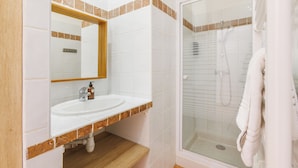 A bathroom with a white sink, a mirror, and a glass-enclosed shower. - Le Domaine de la Mer (Hyères)