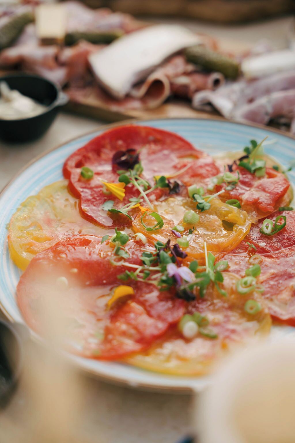 A plate of food with sliced tomatoes, cheese, and greens.