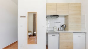 A compact kitchen with white cabinets, a dishwasher, and a compact refrigerator. - Le Domaine de la Mer (Hyères)