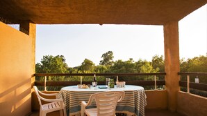 A covered outdoor dining area with a table set for two, surrounded by chairs, overlooking a lush green landscape. - Résidence Marina Corsa (Ghisonaccia)