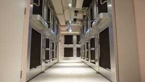 Un pasillo con varias puertas de ascensor, techo con conductos de ventilación y un artefacto de iluminación.