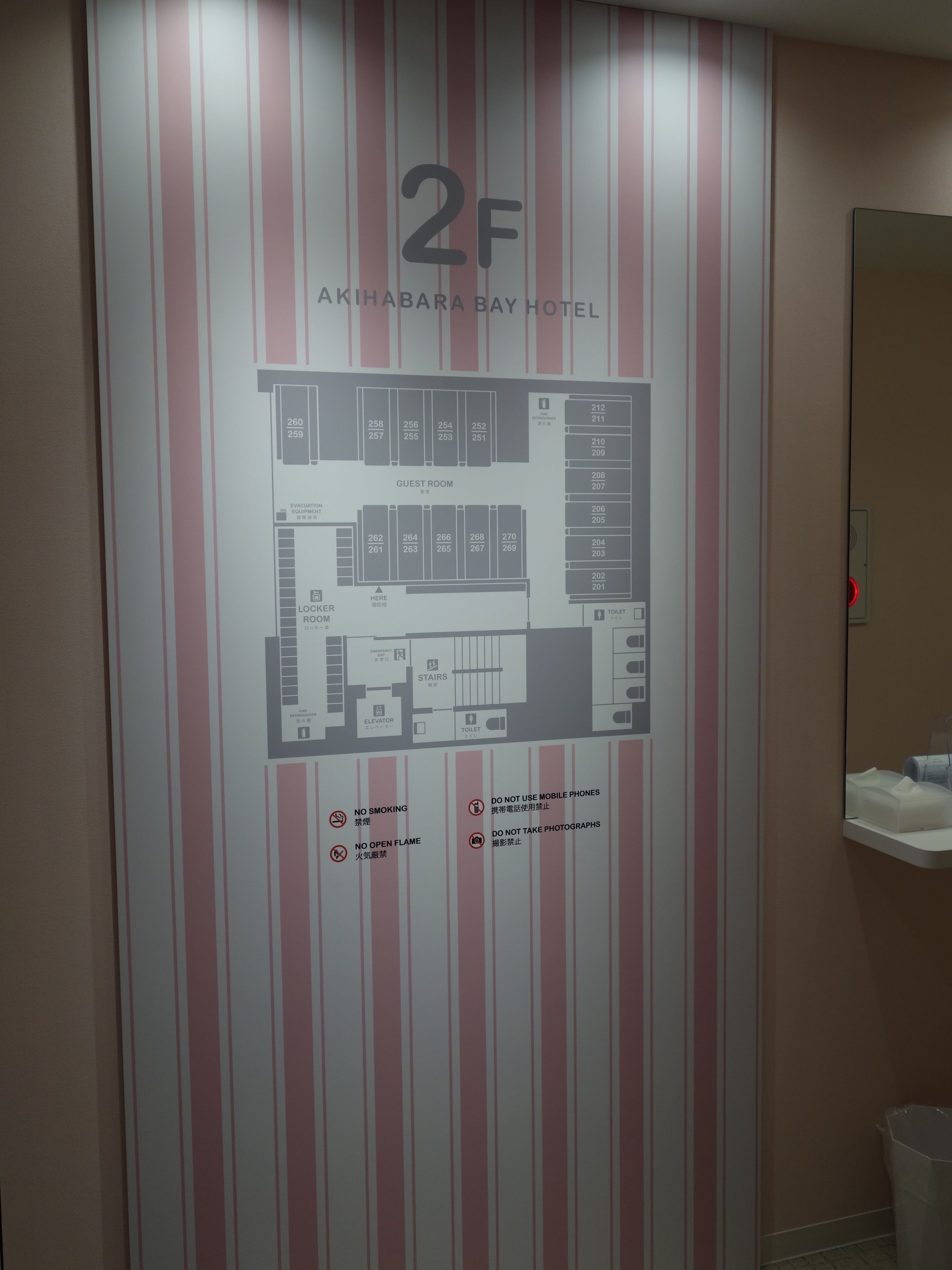 Plan d’un hôtel comprenant une chambre pour les clients et un vestiaire, avec indication des numéros de chambre et des équipements tels que des toilettes et un ascenseur.