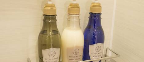 A bathroom shelf with three bottles of ESTHE ROYER body soap, conditioner, and shampoo.