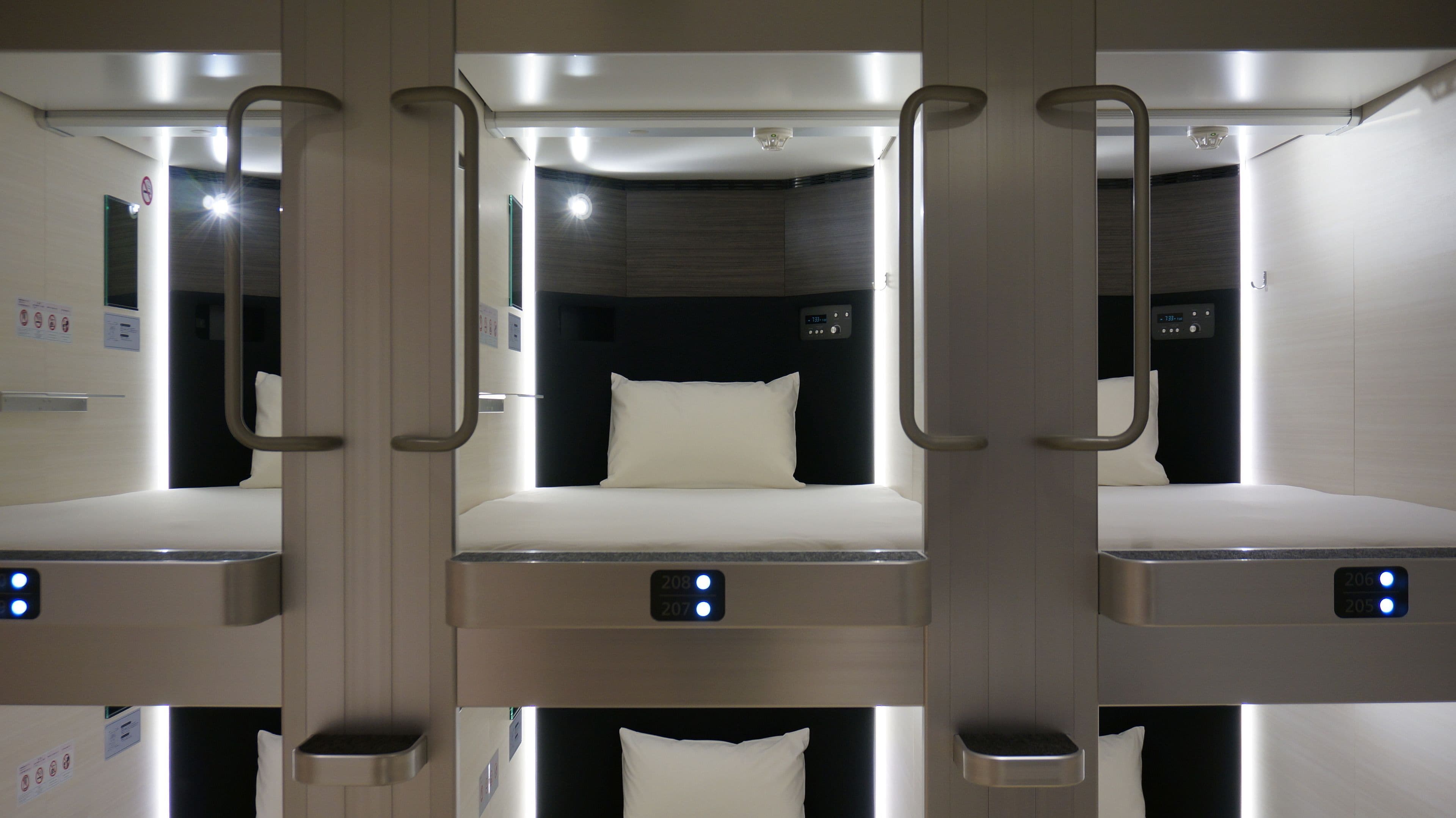 A hotel room with three beds arranged in a row, each with a control panel and a pillow.