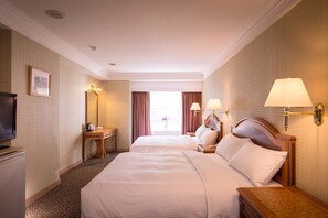 A hotel room with two beds, a television, a desk with a lamp, and a window with curtains. - Green World Flora Annex (Taipei)