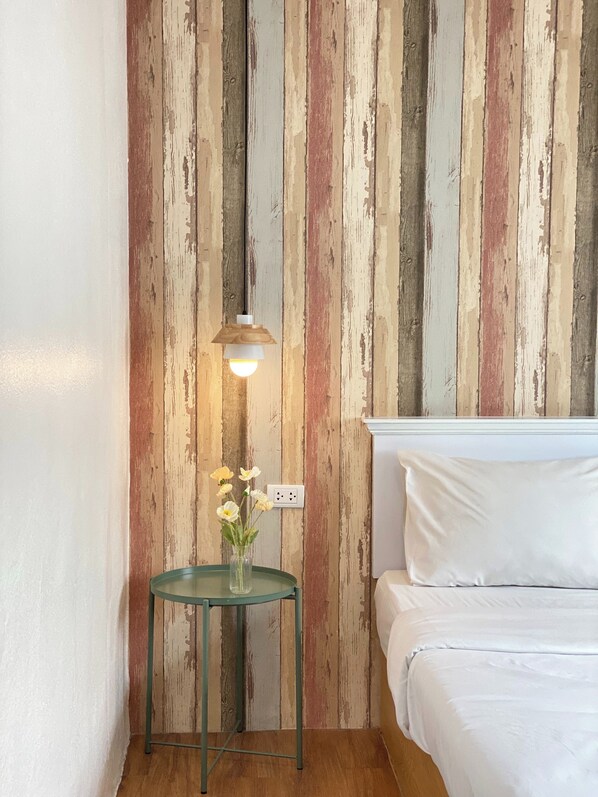 A room with a bed, a nightstand with a lamp, and a wall with a vertical striped pattern. - Sleep at Phuket (Phuket)
