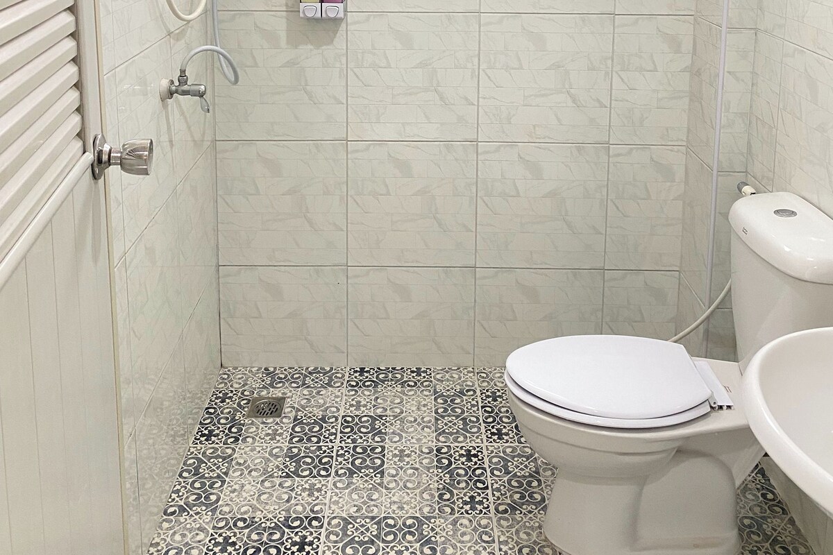 Une salle de bain avec une douche, des toilettes et une fenêtre.