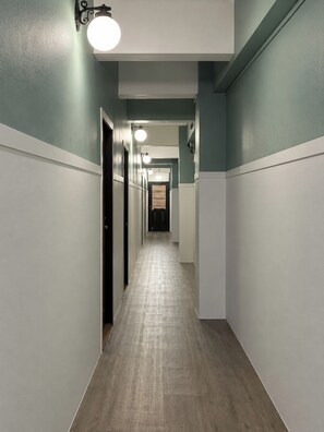 A hallway with a light wood floor, white wainscoting, and teal walls. - Sleep at Phuket (Phuket)