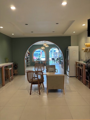 A modern kitchen with a dining area, featuring a large arched window, wooden furniture, and recessed ceiling lights. - Sleep at Phuket (Phuket)