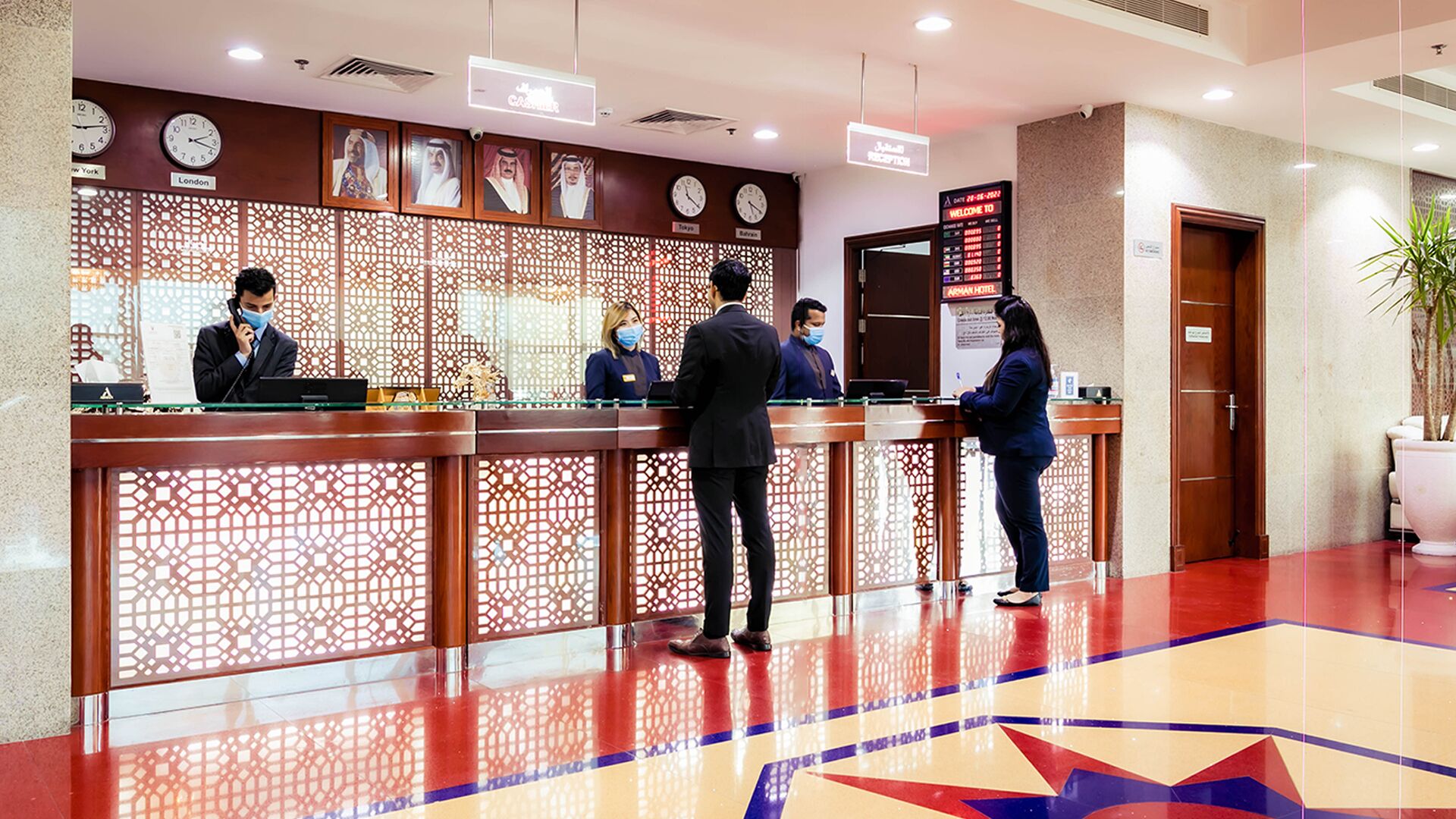 A hotel reception area with a modern design, featuring a reception desk, digital display, and decorative elements.