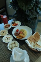 Una mesa con diversos platos, incluyendo un plato de huevos, tomates y queso, cuencos con salsas y una cesta de pan plano.