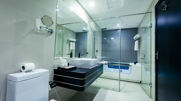 A modern bathroom with a glass-enclosed shower, a bathtub, and a vanity with a black countertop.