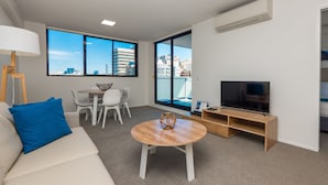 Una sala de estar moderna con un sofá, una mesa de centro, un televisor y un comedor con sillas y una mesa.