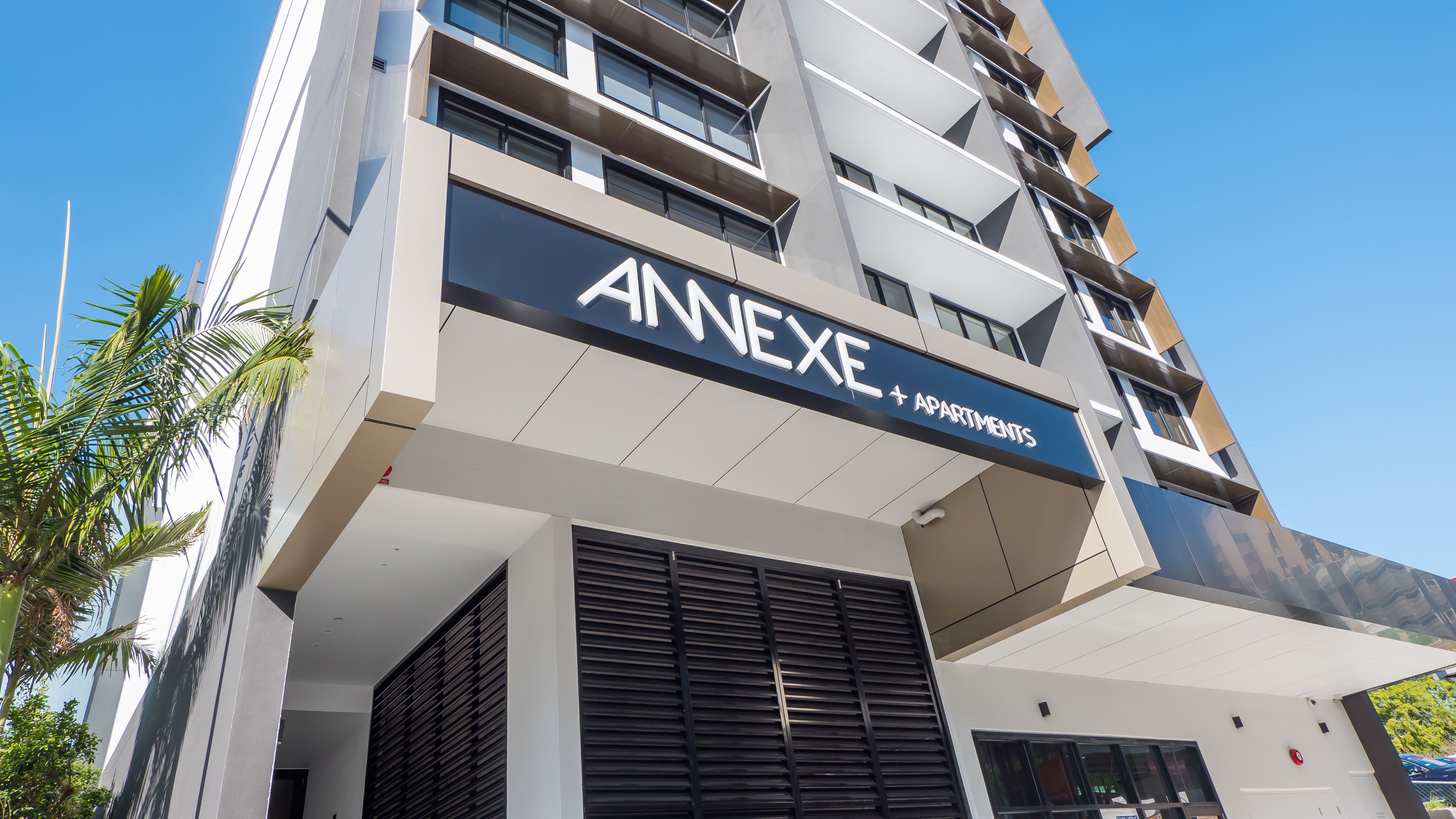Un edificio moderno de varios pisos con un cartel que dice 'ANNEXE + APARTMENTS'.
