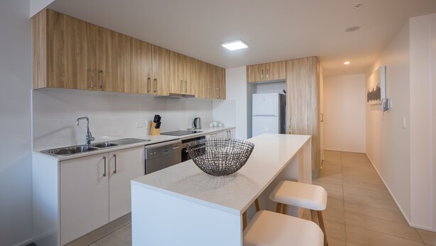 Una cocina moderna con armarios de madera, electrodomésticos de acero inoxidable y encimera blanca.
