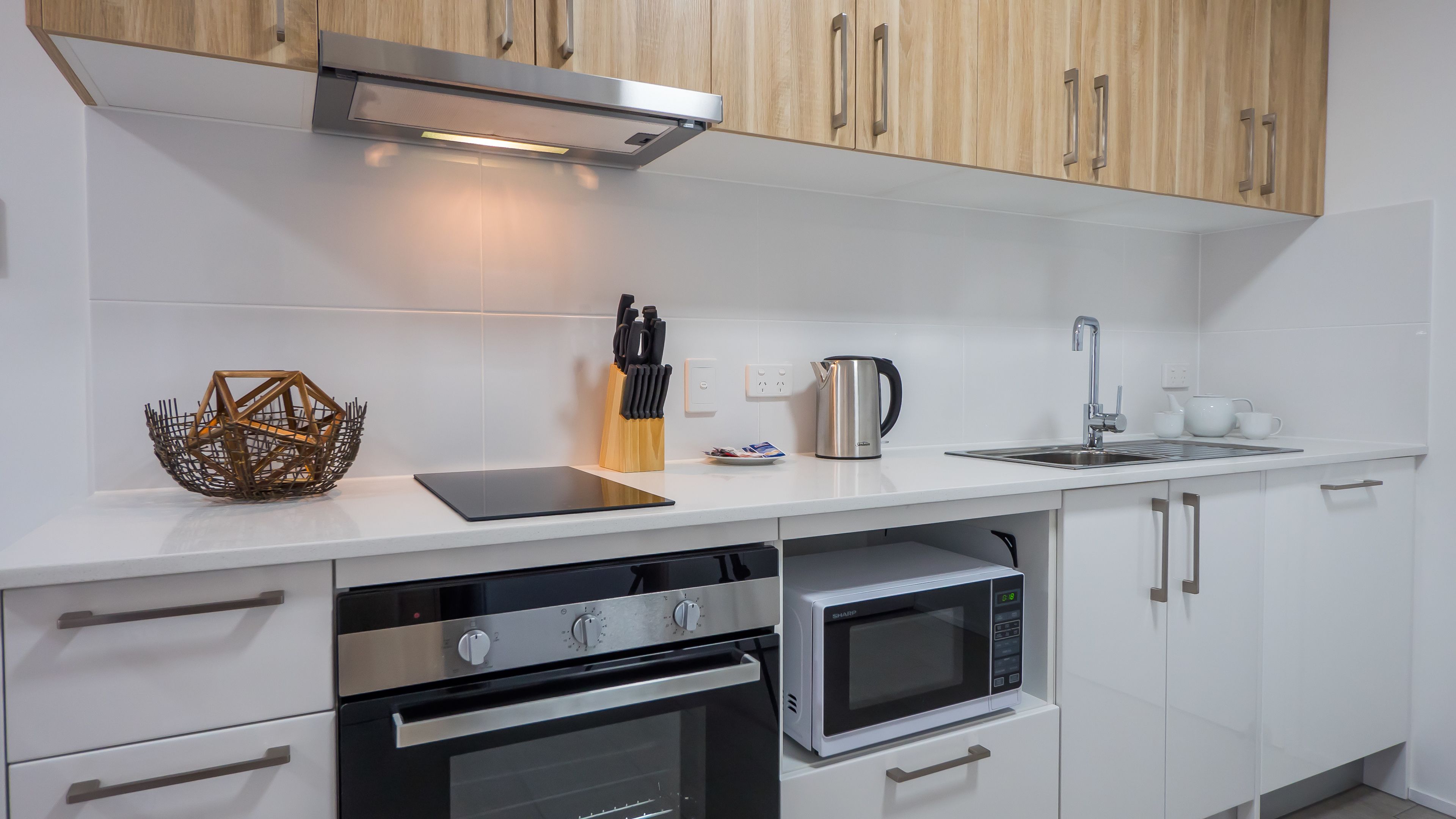 Une cuisine moderne avec des armoires blanches, des appareils en acier inoxydable et un plan de travail en bois.