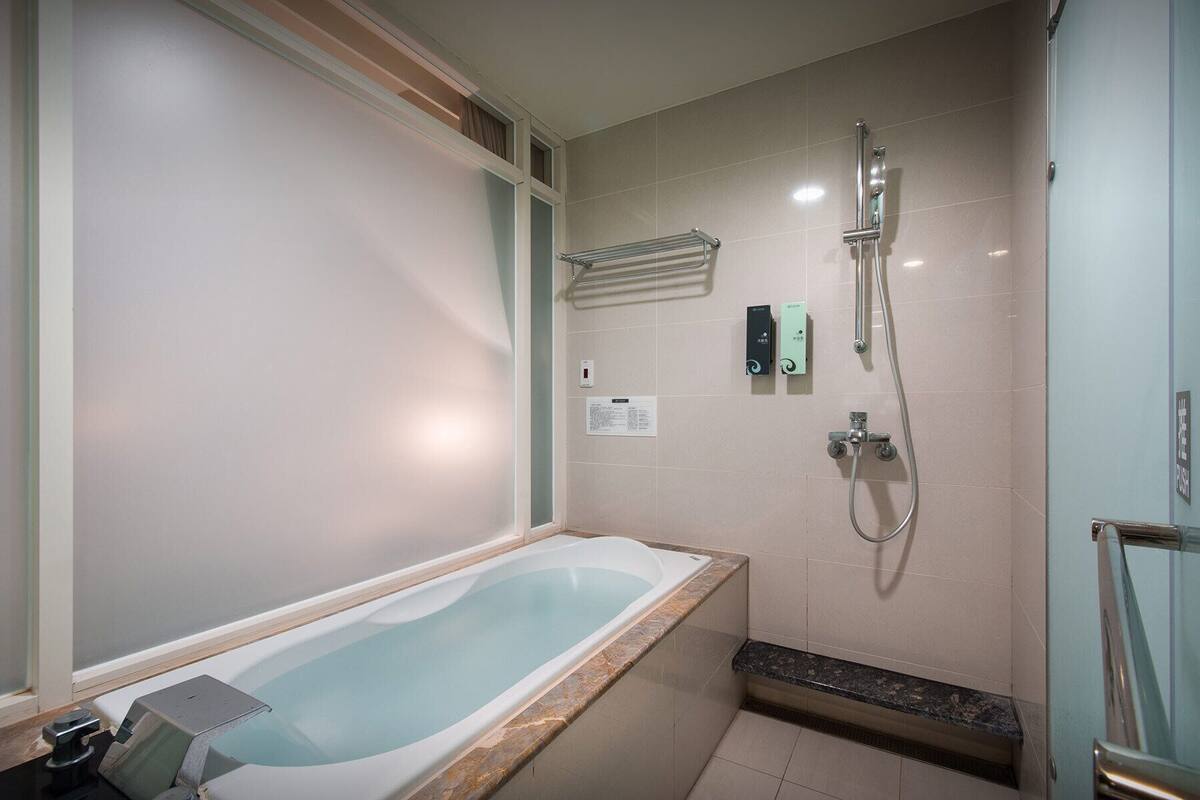 A modern bathroom with a freestanding bathtub, a shower area, and a towel rack.