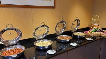 A buffet setup with various food items in covered bowls on a counter.