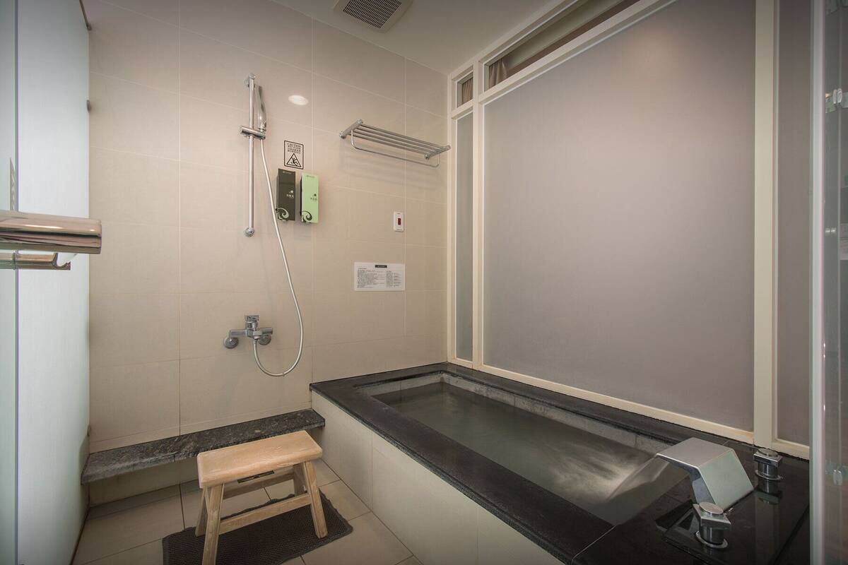 A bathroom with a shower, a bench, and a sink.