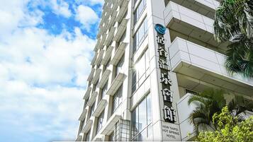 A modern hotel building with a sign indicating it is the New Taipei City Hotel Registration.