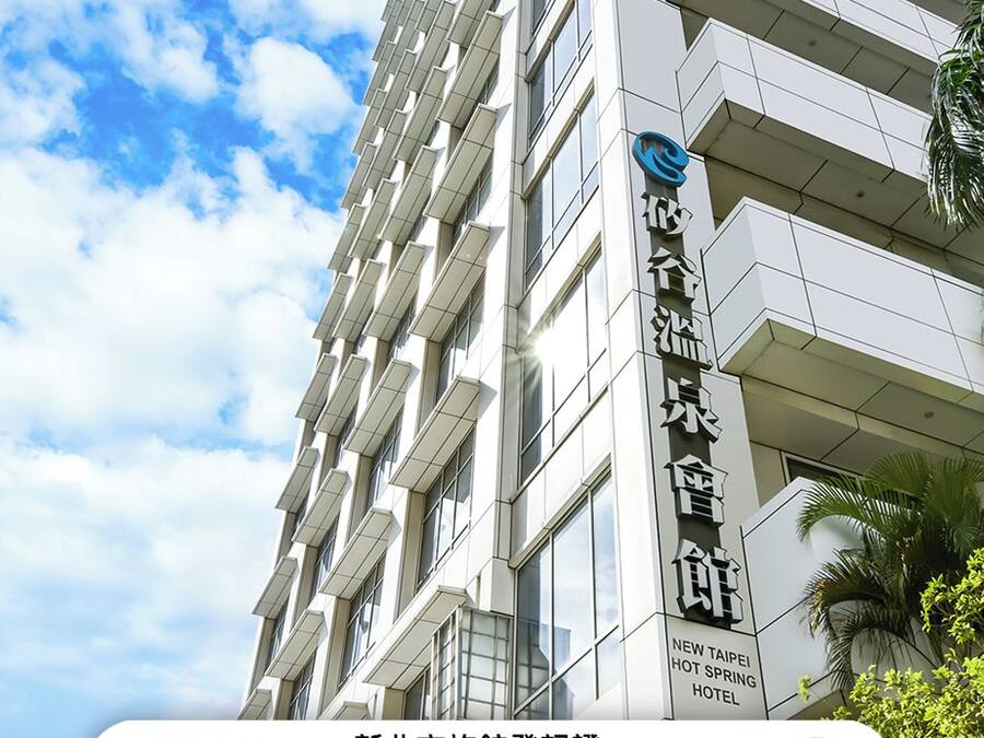 Een modern hotelgebouw met een bord waarop staat dat dit het New Taipei City Hotel is voor de registratie.