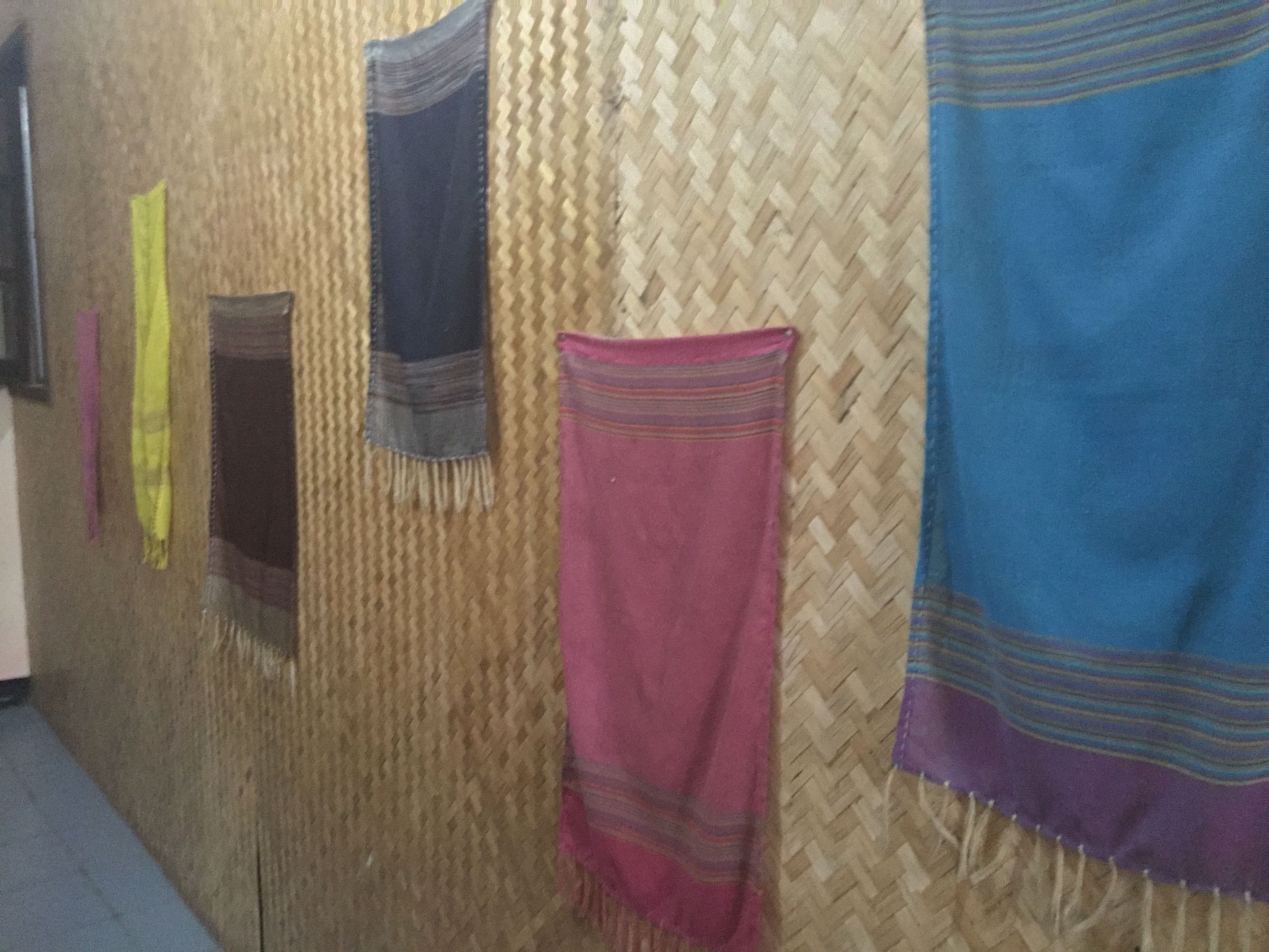 Una habitación con una pared texturizada y varias mantas colgadas.