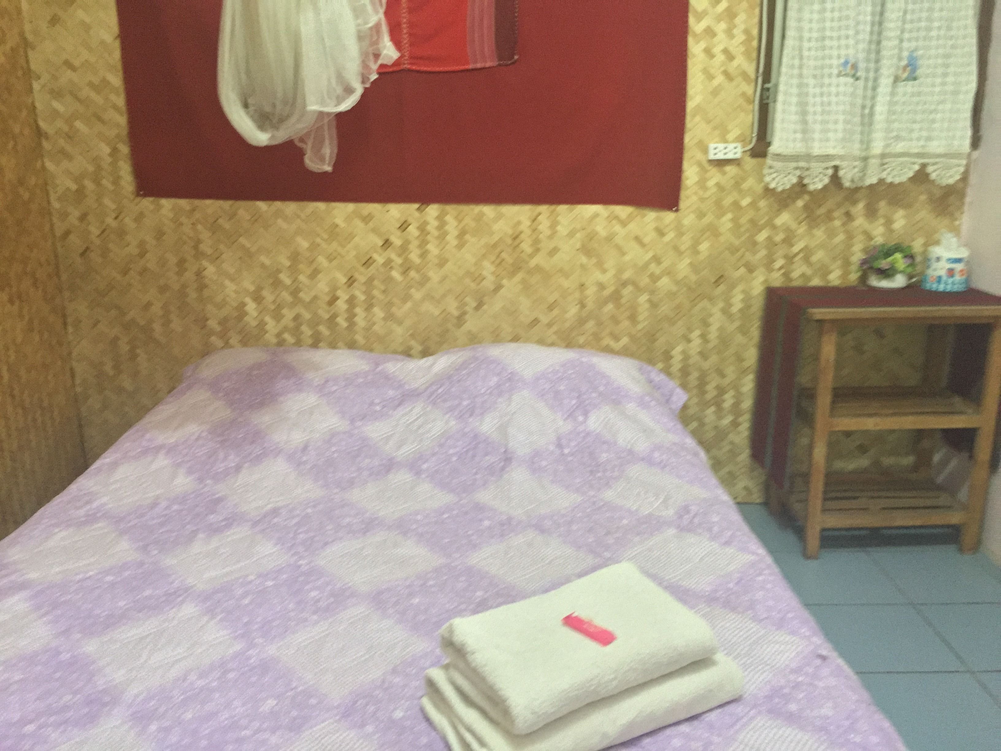 Una habitación pequeña con una cama, una mesita de noche de madera y una ventana con cortina roja.