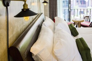 A hotel room with a neatly made bed, a small round table, and a balcony with a view. - Arun Rawee (Chiang Mai)