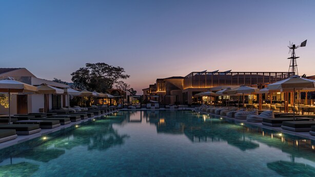 A serene pool area with lounge chairs and umbrellas, surrounded by buildings with a modern architectural style. - Eleonas Boutique Hotel & Spa (Rhodes)