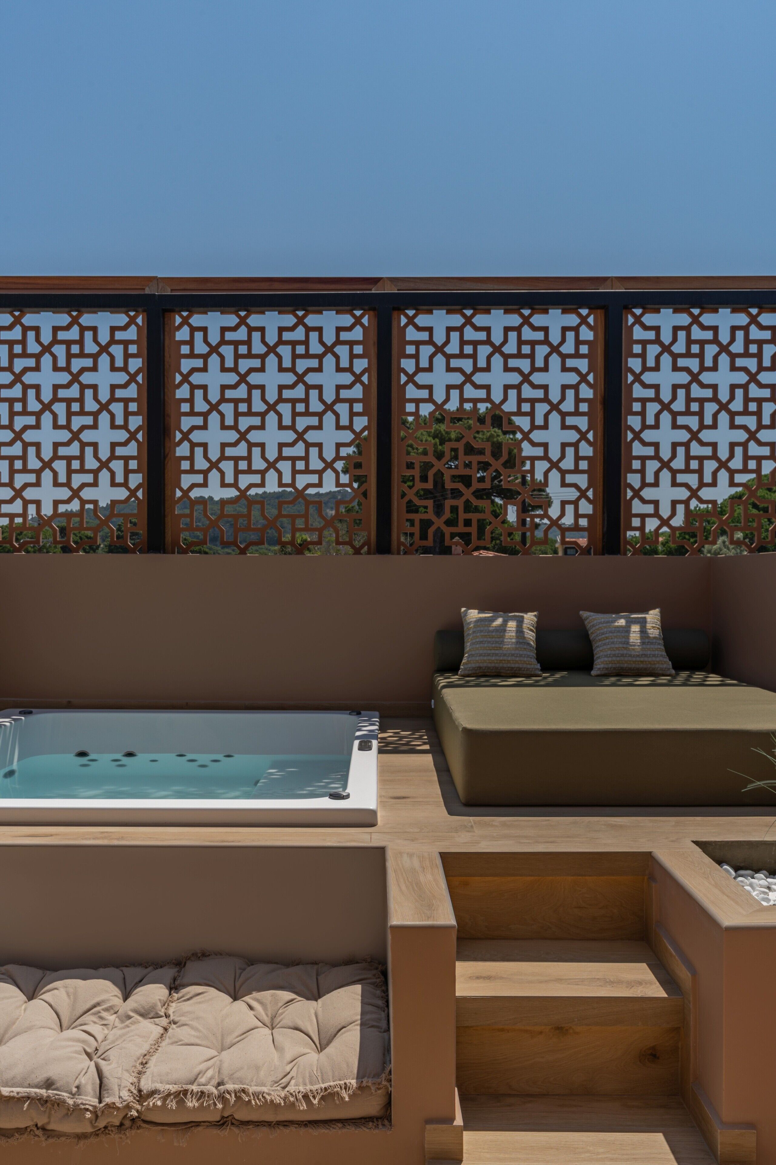 Eine Dachterrasse mit Whirlpool, einer gepolsterten Lounge-Ecke und einem Holzboden.