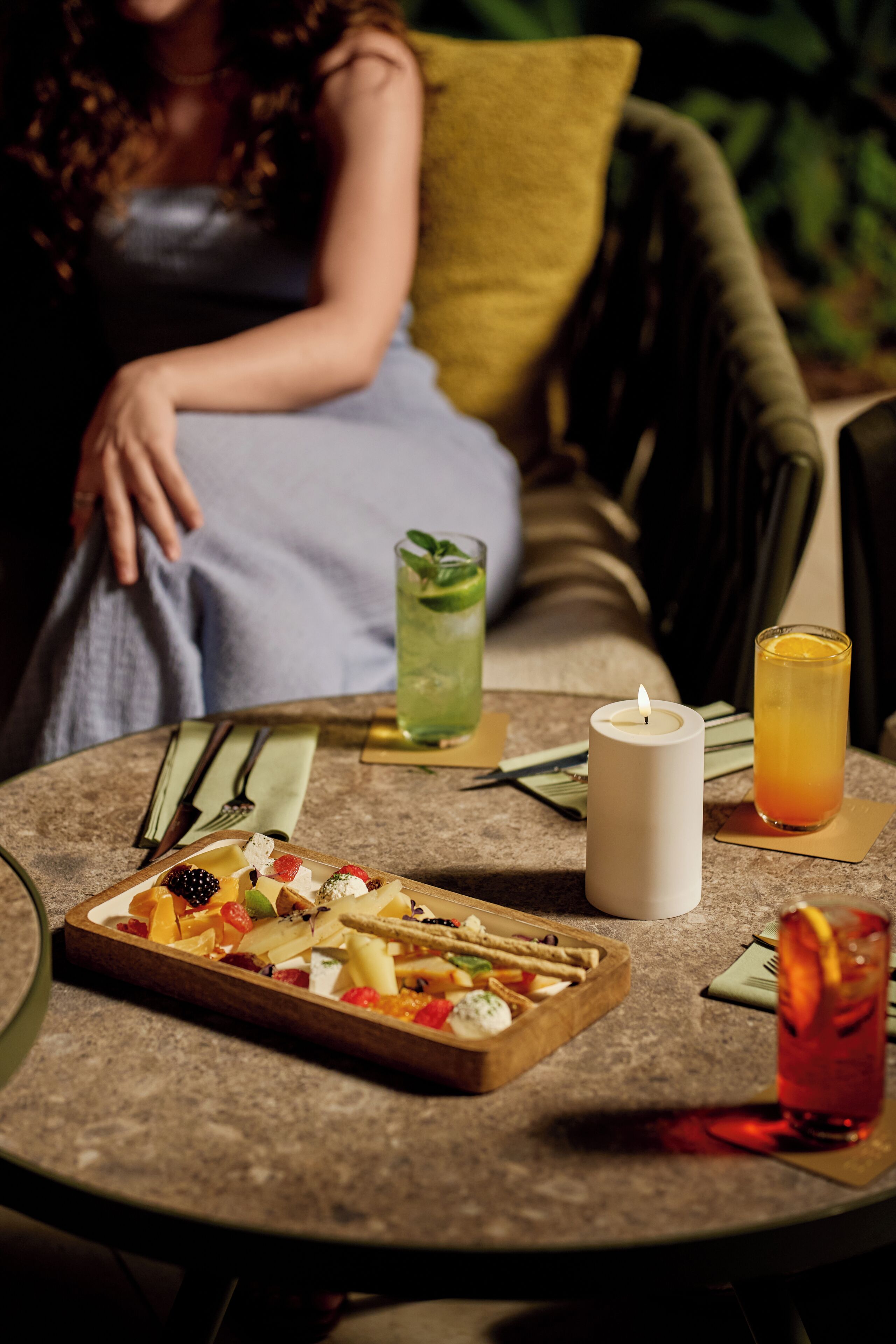 Een ronde tafel met eten, een kaars en drinken.