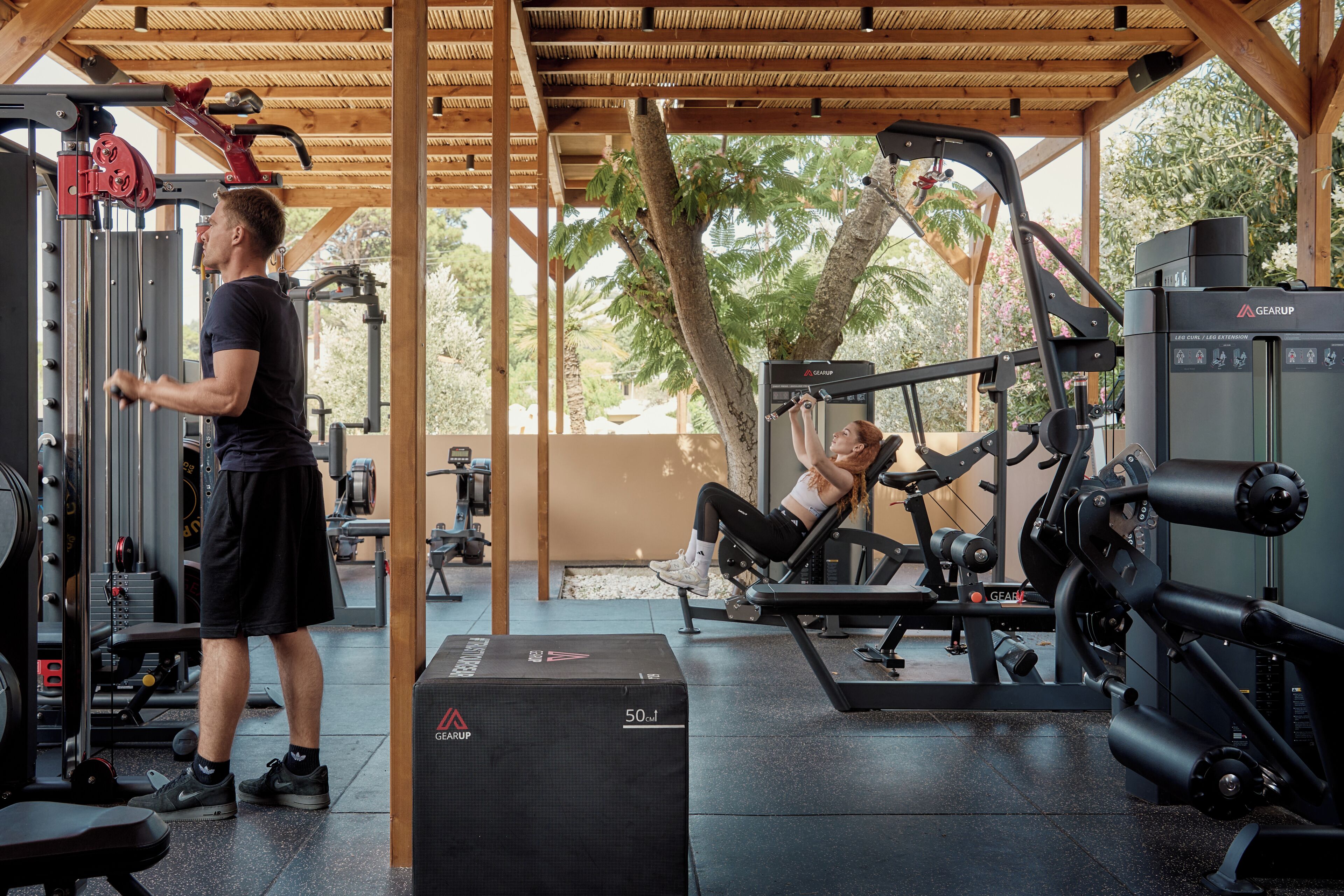A gym with various exercise equipment, including a leg curl machine and a bench press.