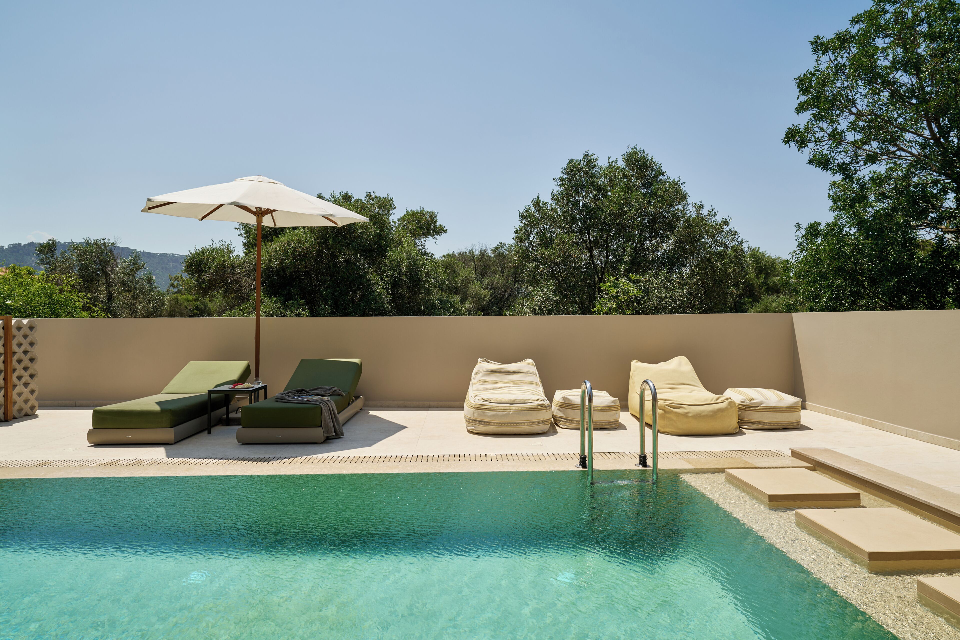 A poolside area with lounge chairs, a sun umbrella, and a clear view of the surrounding landscape.