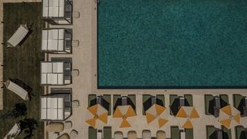 En vy över ett hotell från ovan, med en swimmingpool, solstolar och parasoller.