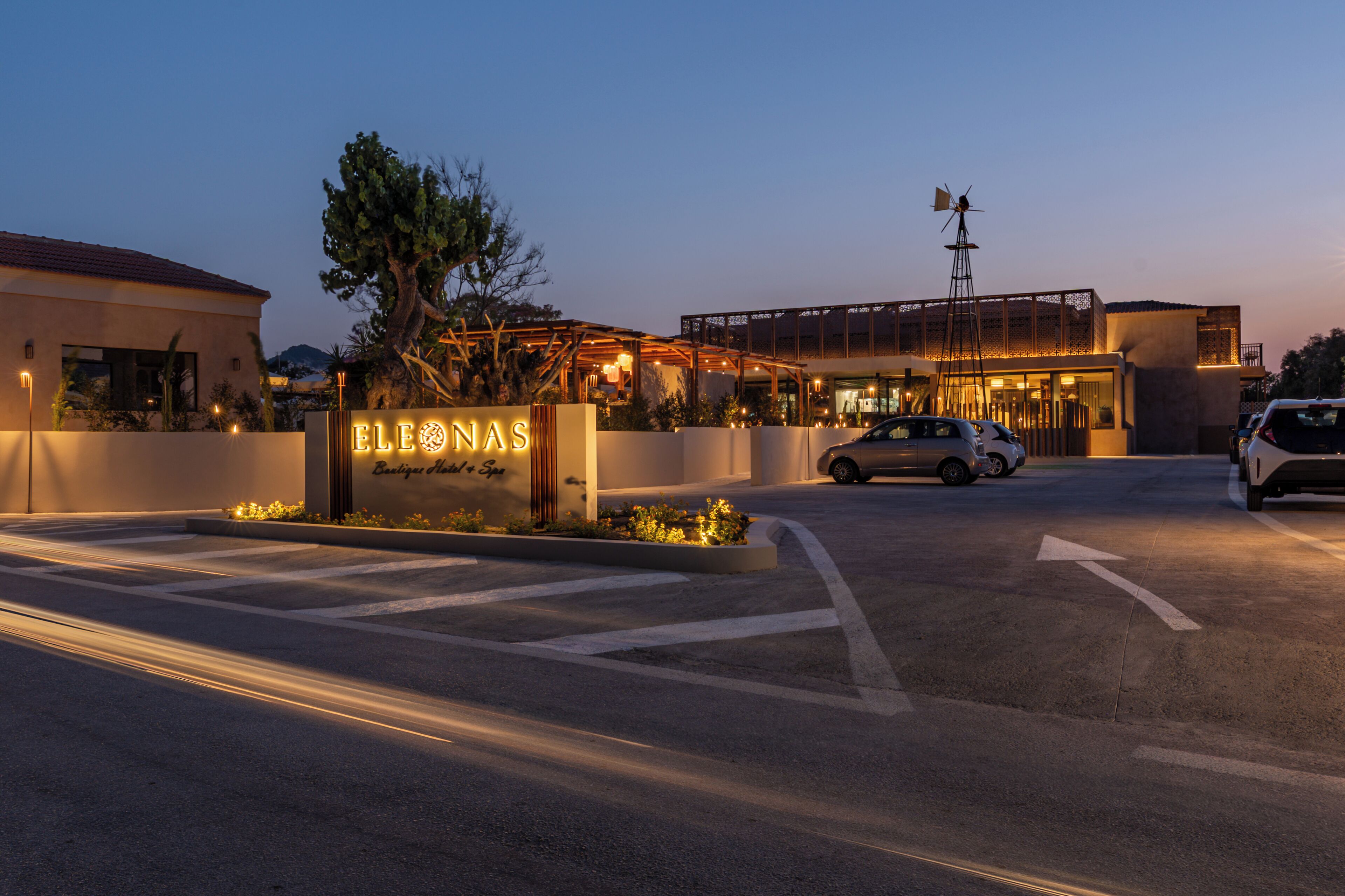 Entrada de hotel com uma placa que diz "ELEONAS" e um edifício moderno ao fundo.