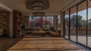 A spacious living area with a large window, a wooden floor, and a modern ceiling light fixture. - Eleonas Boutique Hotel & Spa (Rhodes)