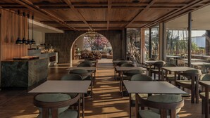 A modern restaurant interior with wooden ceiling beams, a marble counter, and a view through an arched doorway. - Eleonas Boutique Hotel & Spa (Rhodes)