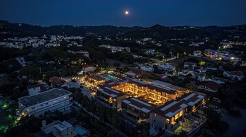 Vista aérea de una zona residencial con un edificio destacado que cuenta con una piscina, rodeado de otras casas y vegetación.