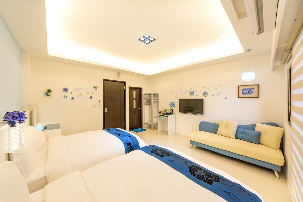 Una habitación de hotel moderna con una cama grande, un sofá, un escritorio y un televisor.