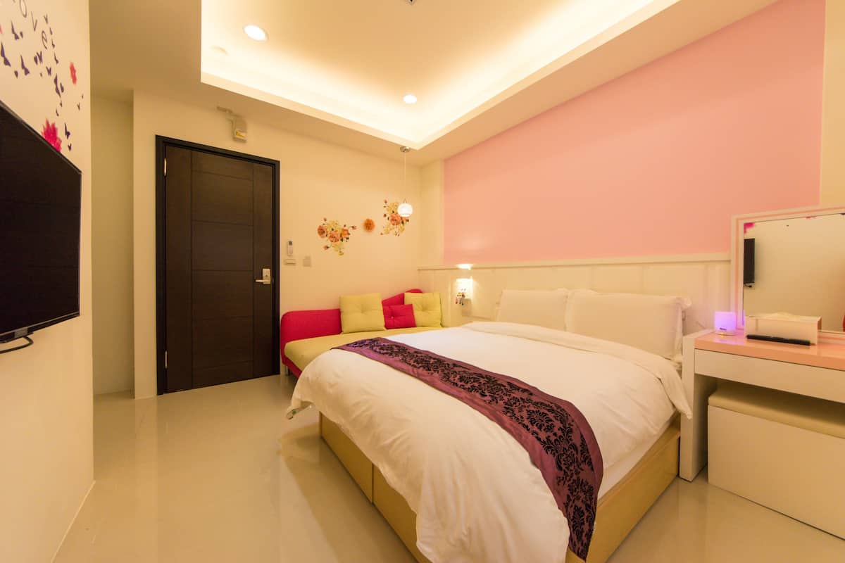 Un dormitorio moderno con una cama grande, una mesita de noche y un televisor montado en la pared.