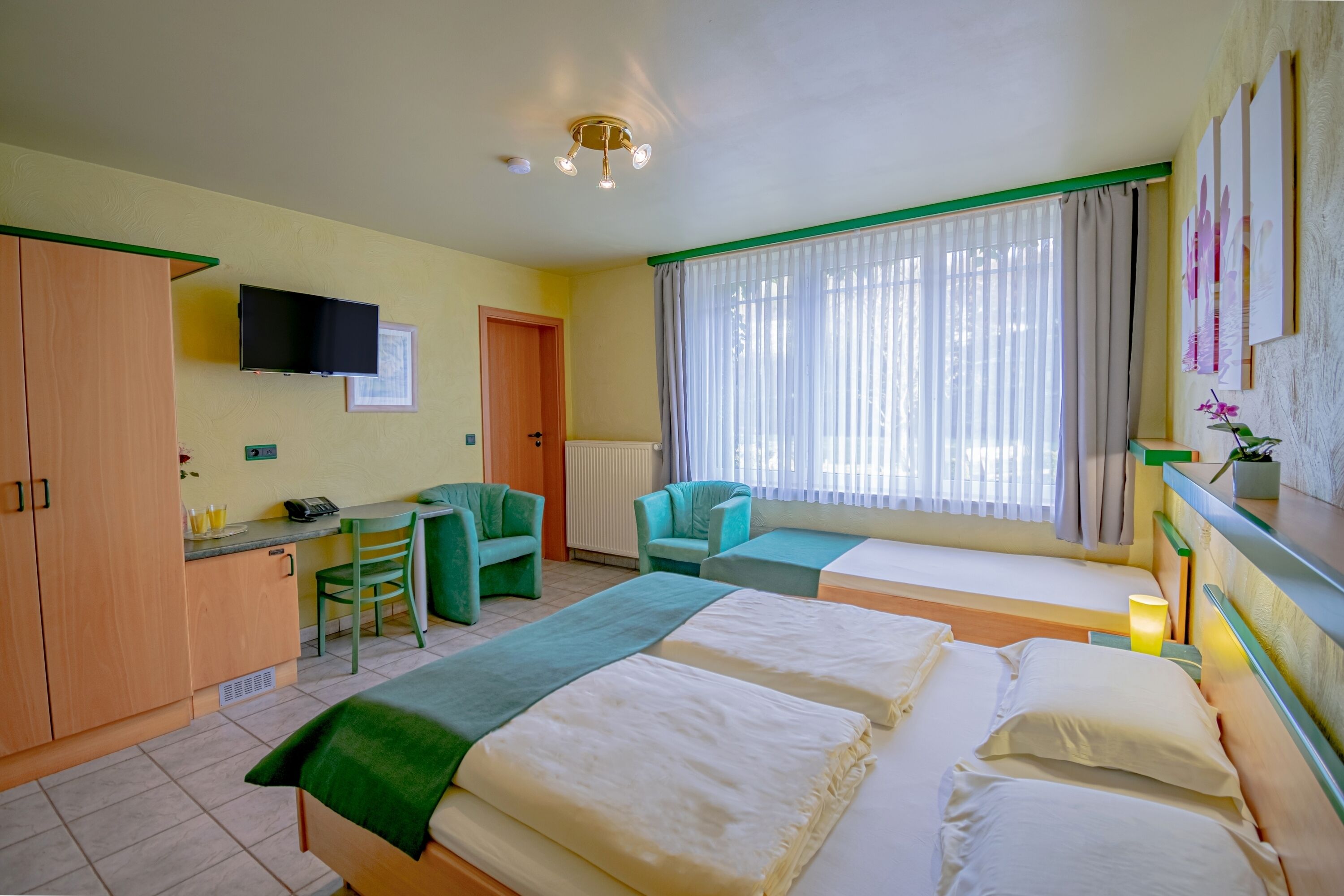 A hotel room with two beds, a desk, a chair, a TV, and a window with curtains.