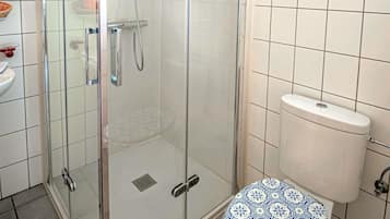 A bathroom with a glass-enclosed shower, a white toilet, and a sink.